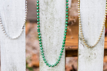 Closeup of colorful mardi gras festival necklace beads, with green color, hanging on wooden fence...