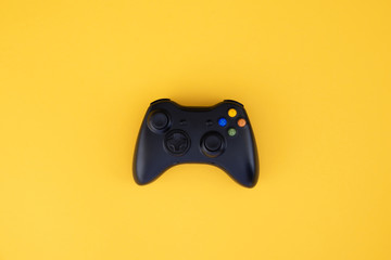 Black gamepad, controller on a yellow background. Computer game competition. Gaming concept. Wireless control of the game.