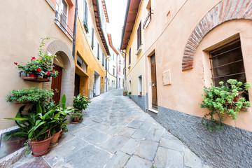 Fototapeta na wymiar Chiusi, Italy street alley in small historic medieval town village in Umbria near Tuscany during sunny summer day, nobody, orange yellow bright vibrant colorful painted walls