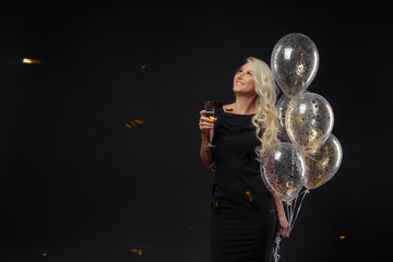 Brightfull expressions of happy emotions of amazing girl celebrating party on black background. Luxury black dresses, smiling, golden tinsels, big balloon, long curly hair, stylish look