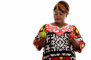 Studio shot of fat black African woman looking at green apple an