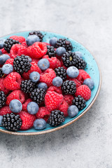 Fresh berry salad on blue dishes. Vintage wooden background.