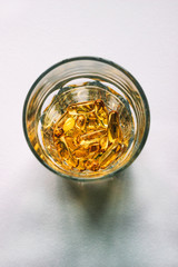 Glass of fish oil capsules on gray background