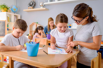 Preschool teacher assisting children with their drawings. Early education. Harnessing creativity...