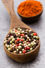 Peppercorn mix in a wooden bowl on grey table.