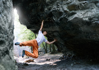 man rock climber climbing on the overhanging cliff