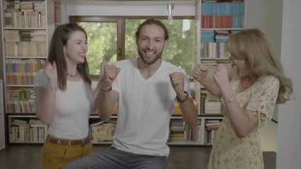 Group of excited students in the library high fiving and jumping celebrating successful exam results