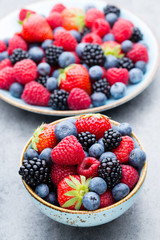 Fresh berry salad on blue dishes. Vintage wooden background.