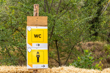 Black pointer on a wooden yellow board in a campsite, toilet and shower sign