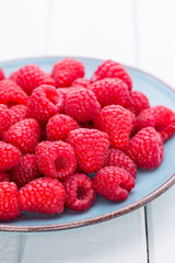 Fresh raspberries in a plate on a  vintage background.