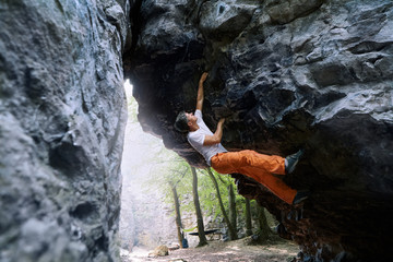 man rock climber climbing on the overhanging cliff