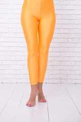 sport wear fashion. orange. practicing in ballet studio. woman in orange leggings on legs. dancing ballet position of feet. A Trendy Dance. Desire meets dance. Your Favourite Dancing Academy.