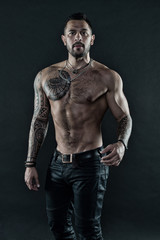 Fototapeta na wymiar Handsome fit man posing wearing in jeans with tattoo. Tattoo art. Man handsome shirtless muscular with jeans over dark background. Muscular tattooed athlete look attractive. Sport and fashion concept