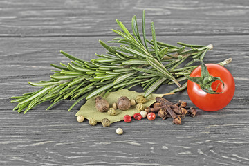Plakat Rosemary, laurel leaf, pepper, cloves and cherry tomato on wooden background