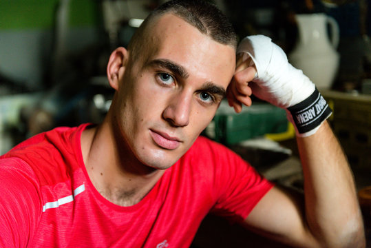 ragazzo con t shirt rossa e fasce da boxe, in un'officina