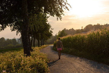 Junge Frau spaziert in der Natur gegen Sonnenuntergang