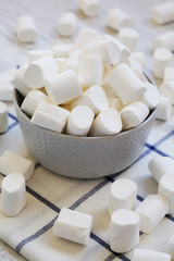 Fototapeta na wymiar Sweet white marshmallows in a grey bowl, side view. Close-up.