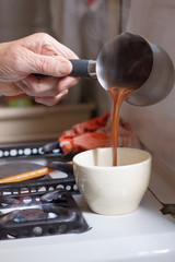 Hands of old woman serving coffee on a cup