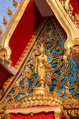 Close-up of a Buddha statue and ornate and intricate facade of the Buddhist Wat Chanthaburi (Chanthaboury) Temple in Vientiane, Laos, on a sunny day.