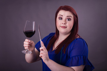 Young female clinging a glass of red wine butter knife getting attention for toast 