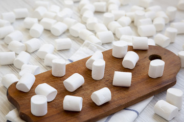 Fototapeta na wymiar Sweet marshmallows over white wooden background. Heap of fluffy marshmallows. Side view.
