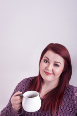 Pretty young woman holding cup of coffee framed vertically subject lower bottom right