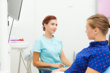 female dentist communicates with a female patient in the treatment room