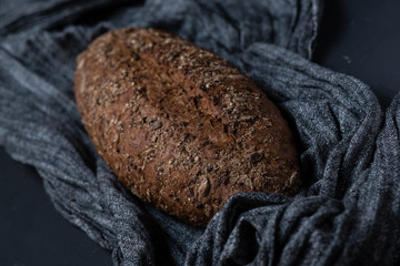 Whole grain bread with seeds on a gray fabric on a textured surface