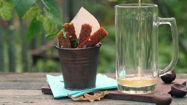 Beer pouring on wooden table outdoors and garlic rye croutons