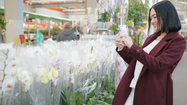Woman in garden shop using smartphone taking a picture