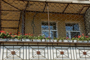 Fototapeta na wymiar large balcony with iron grill with flowerpots and decorative flowers