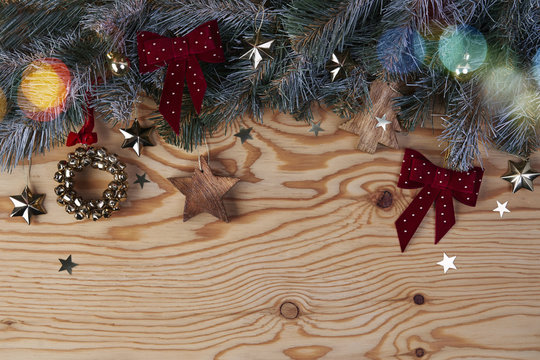 Christmas background with fir tree and decoration on light wooden board from above..