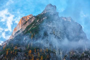 Panorama of Dachstein mountains peaks with sunset light Austria. Peaks covered with clouds