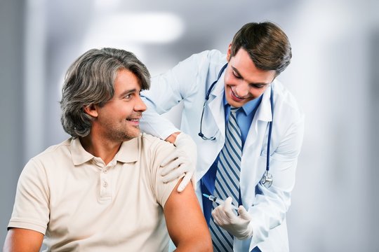 Handsome doctor making vaccination to male patient