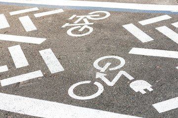 Fototapeta premium Asphalt road with bicycle and electric transport lane. Cycle and zero emission vehicles white sign on floor. Recreation area for green energy transport in city park