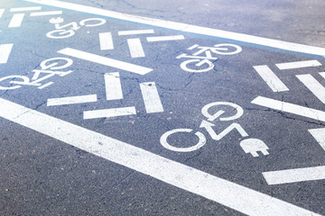 Fototapeta premium Asphalt road with bicycle and electric transport lane. Cycle and zero emission vehicles white sign on floor. Recreation area for green energy transport in city park