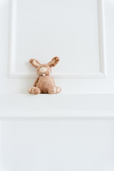 old plush brown retro hare on white wall background
