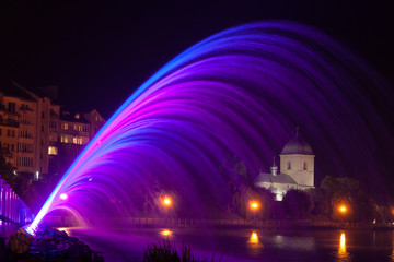 Coloured fountain water jets at night near the lake