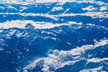 Blue planet Earth seen from high above through an airplane window. Unique panoramic high altitude aerial view of thunderstorm clouds cumulus over snow-capped mountain region of south central Europe.