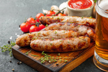 Fried sausages with sauces and herbs on a wooden serving Board. Great beer snack on a dark background. With copy space
