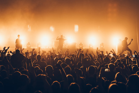 silhouettes of concert crowd in front of bright stage lights. A sold out crowd on rock concert. Crowd of fans at music festive. Party in nightclub.