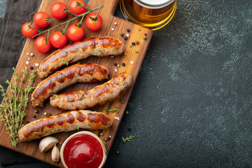 Fried sausages with sauces and herbs on a wooden serving Board. Great beer snack on a dark...