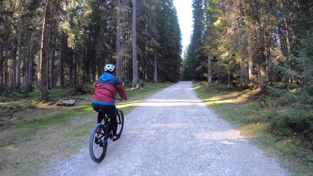 Tracking shot. Woman on mountain bike on a gravel forest road.