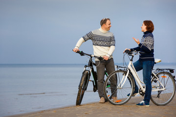 Fototapeta premium Cheerful young couple biking on beach outdoors