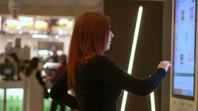 beautiful woman at the vending machine choosing the product to buy