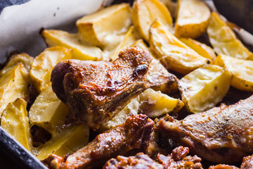 Baked meat with potatoes. Duck meat with golden crust on baking sheet. Cooked in oven dish on parchment. Golden sliced potatoes with chicken meat. Home kitchen
