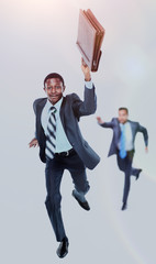 Happy afroamerican man running with a briefcase in hand. in the background- his colleague, trying to catch up him.