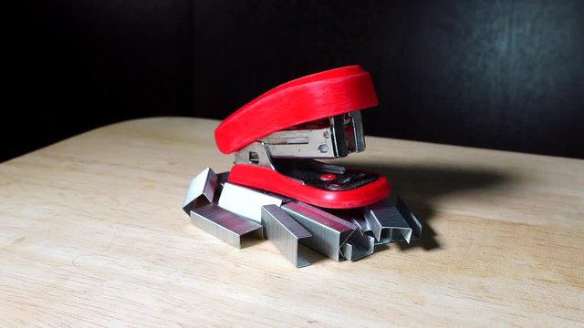 Mini red stapler with silver staples on wooden table isolated indoors