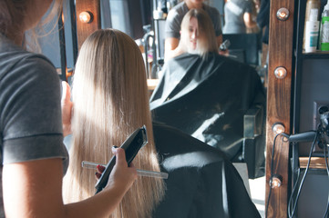 Obraz na płótnie Canvas A beautiful european blonde girl doing a hairstyle in a beauty salon