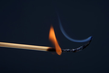Burning match on a dark blue background
